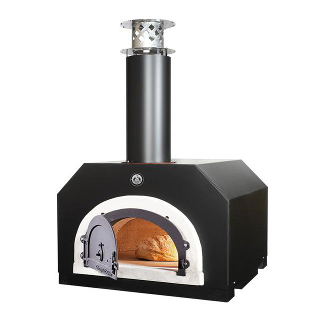On a white background sits the sleek and modern CBO 500 Countertop from Chicago Brick Oven. This wood-fired pizza oven, featuring a stainless steel chimney, has its door slightly ajar, revealing a bread loaf baking on its 27" x 22" stone cooking surface. Crafted with commercial-grade refractory cement, this outdoor pizza oven ensures exceptional heat retention and durability.